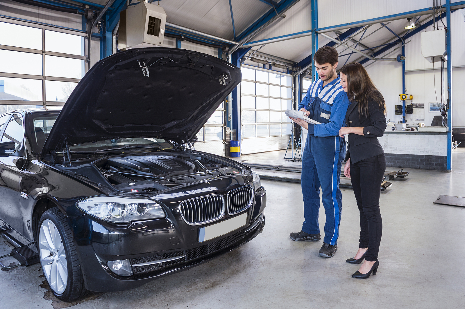 Car mechanic and customer stand next to the serviced car and loo